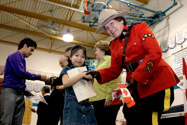 Angelica Detablan, 7, is handed her citizenship certificate and a Canadian flag by RCMP Const. Gerri Beardy at a ceremony at Charleswood School in Winnipeg, Manitoba.